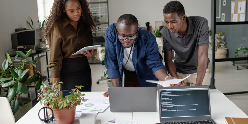 African American team of young and successful developers discussing and creating new codes in white office