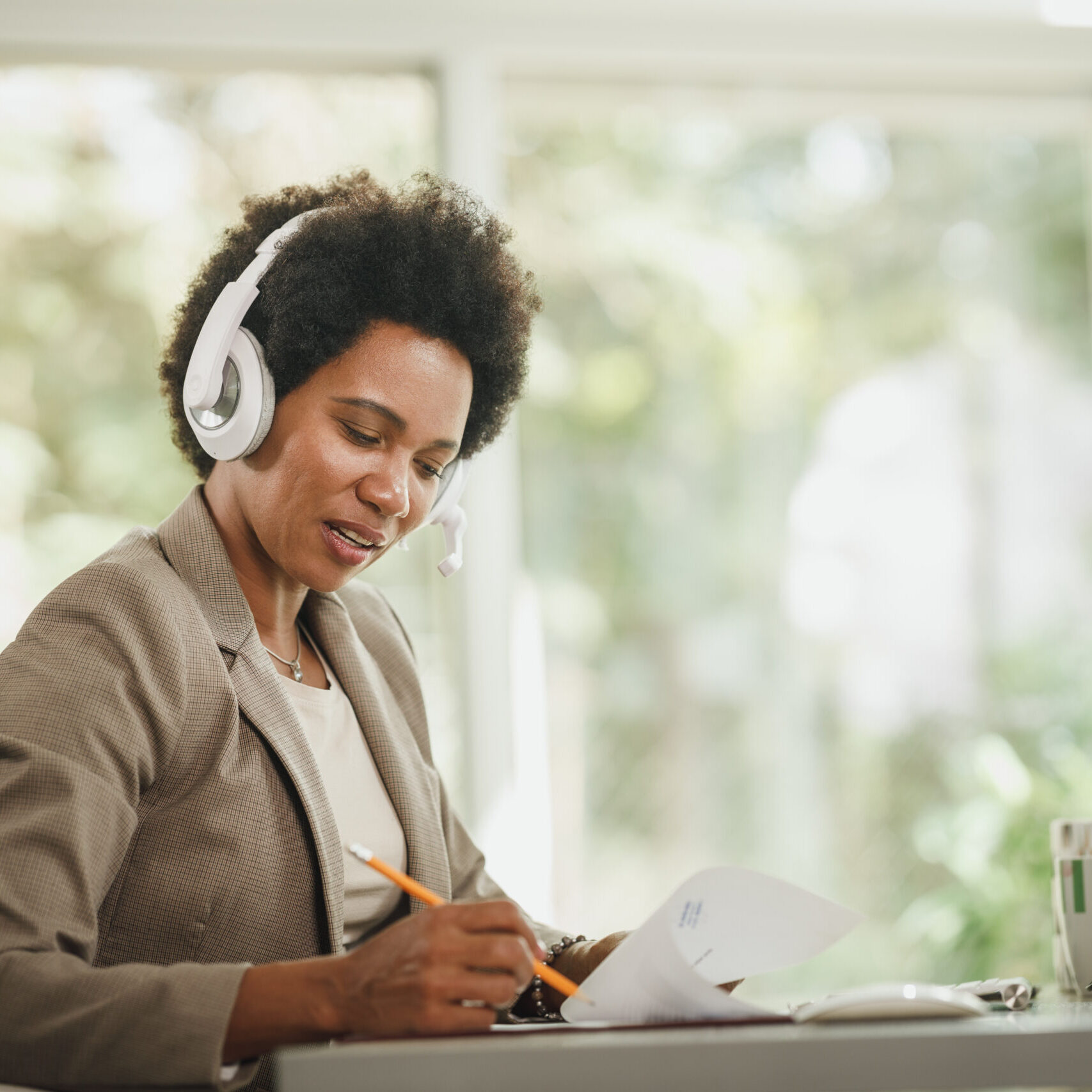 Getting The Task Done From Home Shot of an African woman wearing a headphones and working at her desk during corona virus pandemic.