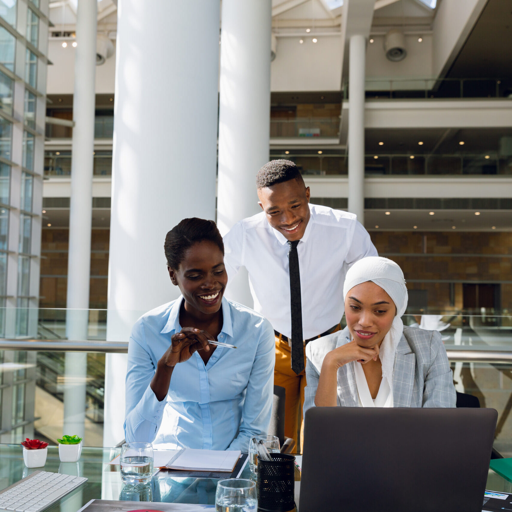 Male and females executives discussing over laptop at desk in office. Modern corporate start up new business concept with entrepreneur working hard Male and females executives discussing over laptop at desk in office. Modern corporate start up new business concept with entrepreneur working hard