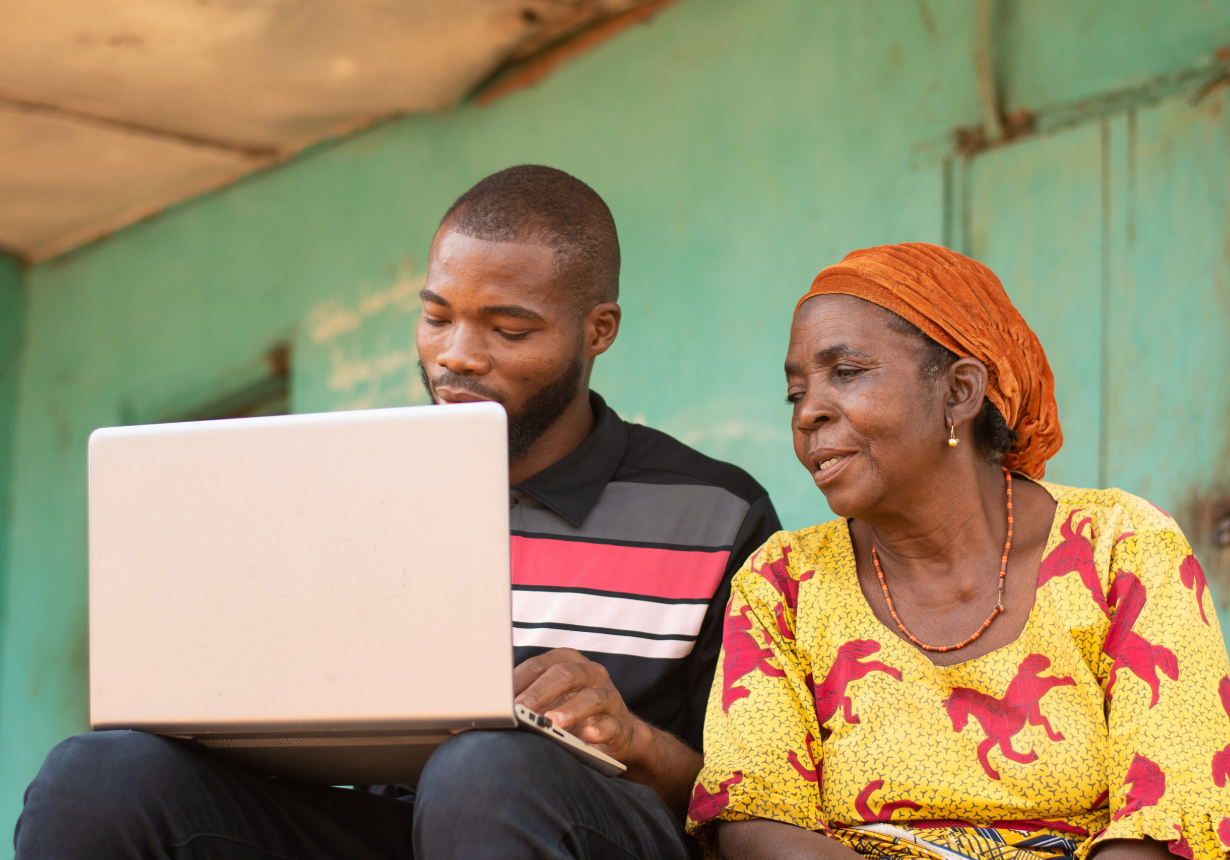 A young black male teaching his older mother how to use technology